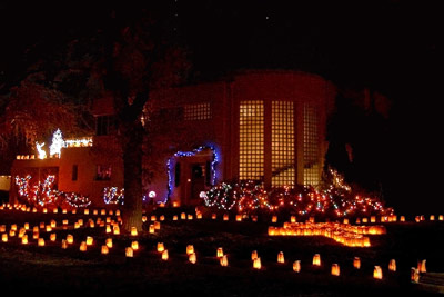A photographic image of a fancy house adorned in Christmas lights.