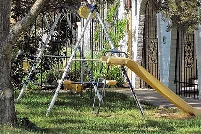 A photographic image of a swing set near a tree.