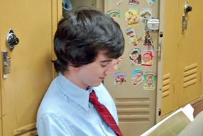 A photographic image of a teenage boy reading.