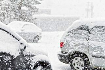 A photographic image of automobiles covered by falling snow.
