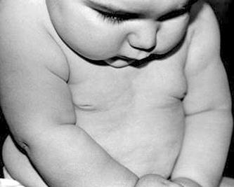 A photographic image of a baby looking down.