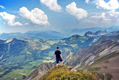 A photographic image of a man standing on top of a mountain.