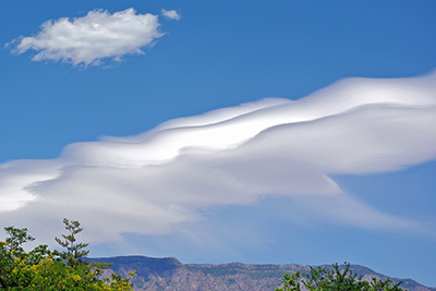 A photographic image of virga flowing out of a mountain wave cloud.