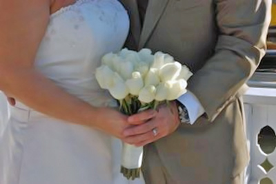 A photographic image of hands holding a wedding boquet.