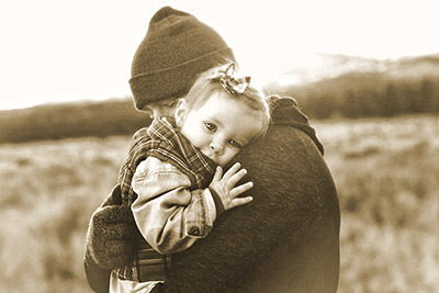 A photographic image of a father holding a baby girl.