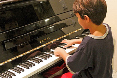 A photographic image of a boy playing a piano.