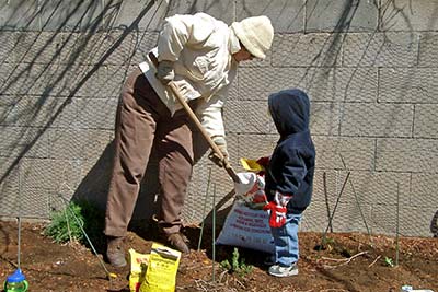 A photographic image of a grandmother, and her grandson, working in a garden.
