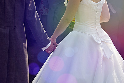 A photographic image of newlyweds holding hands.