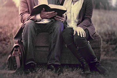 A photographic image of a couple reading outdoors.