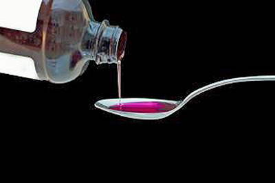 A photographic image of cough syurp being poured into a spoon.