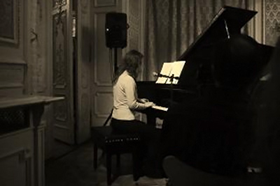 A photographic image of pianist playing in a dark room.