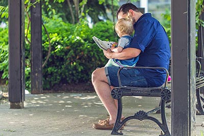 A photographic image of a father reading to a baby.