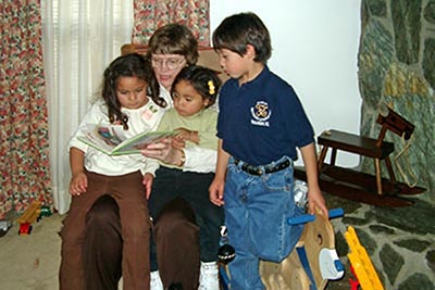 A photograpic image of Mary Hunt Webb reading to the Jaime [Hy'-may] children.