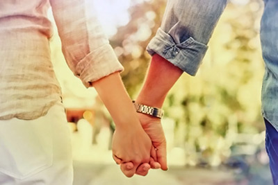 A photographic image of a couple hand-in-hand.