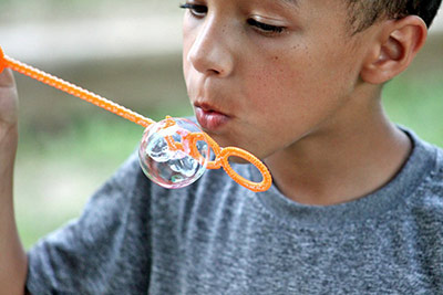 A photographic image of a child blowing bubbles.