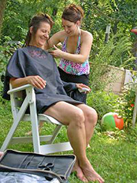 A photographic image of a woman getting a haircut from her friend.