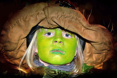 A photographic image of a child with green makeup.