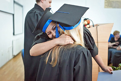 A photographic image of graduates hugging.