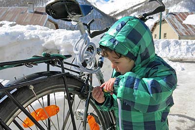 A photographic image of a child repairing a bicycle.