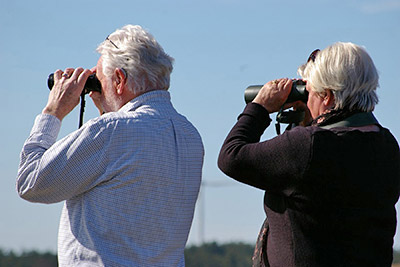 A photographic image of a couple with binoculars.