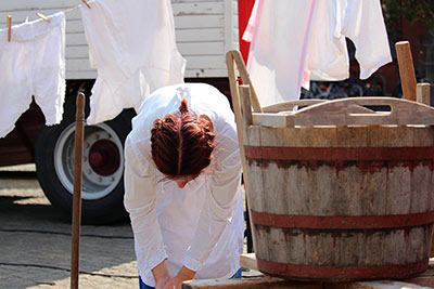 A photographic image of a woman and her washtub.