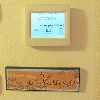 A photographic image of a thermostat and a Count Your Blessings plaque.