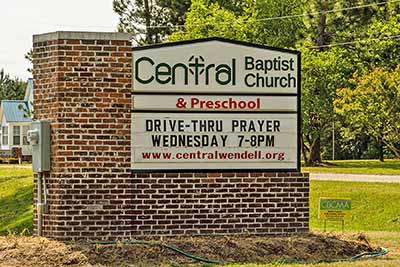 A photographic image of a sign in front of a church.