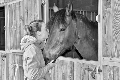 A photographic image of a girl kissing a horse.