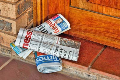 A photographic image of newspapers on a front porch.