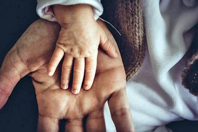 A photographic image of a child's and a parent's hands.