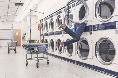 A photographic image of a girl's legs sticking out of a laundromat's dryer.