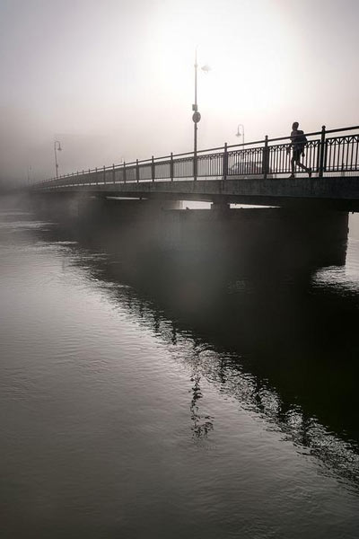 A photographic image of a bridge in fog.