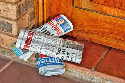 A photographic image of newspapers on a front porch.